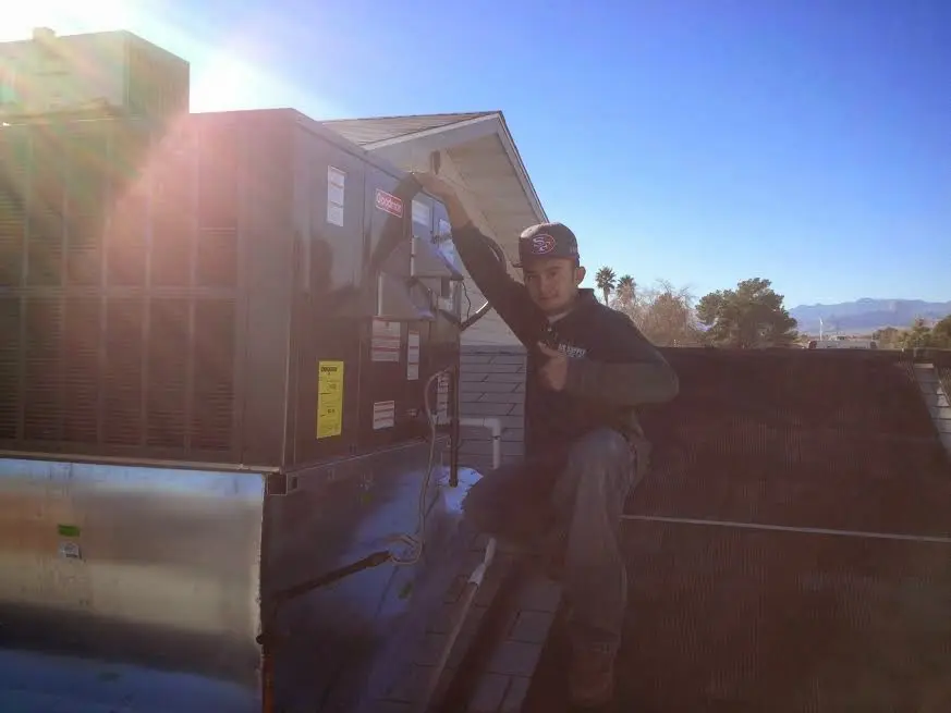 HVAC technician performing Air Duct Cleaning on a rooftop unit in Kochville
